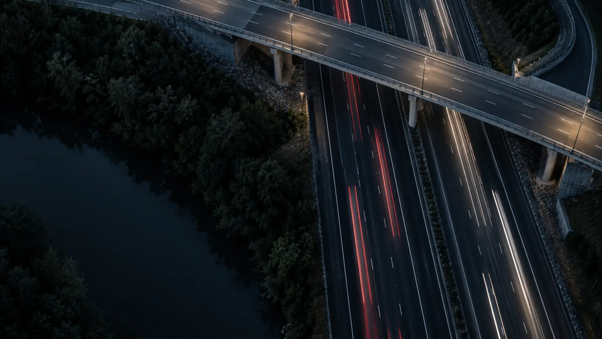 Motorway traffic light trails passing under an overpass at blue hour